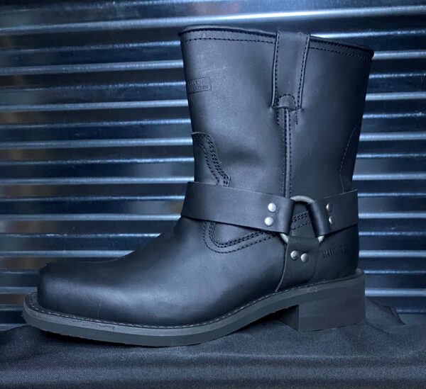 A black leather boot sitting on top of a metal surface.