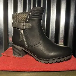 A black boot sitting on top of a red blanket.