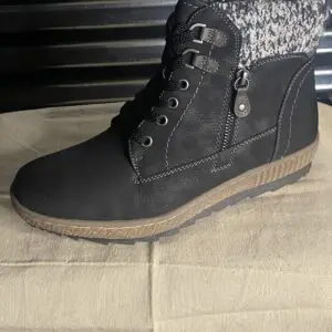 A person wearing black boots on top of a brown table.