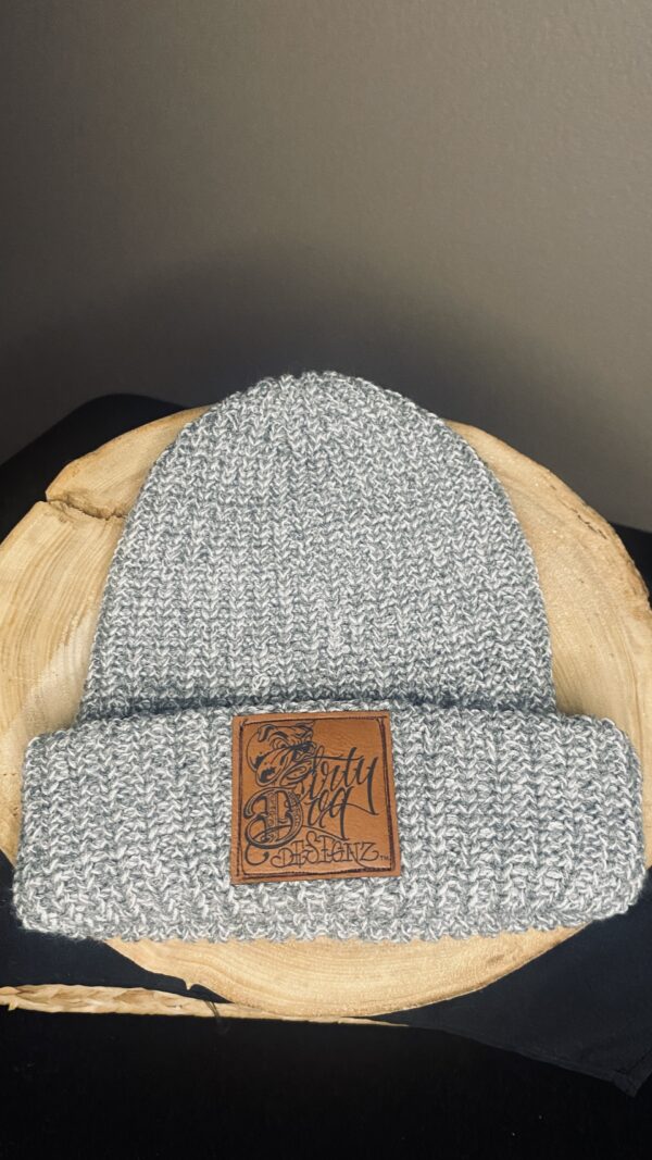 A gray beanie with a leather patch on top of it.